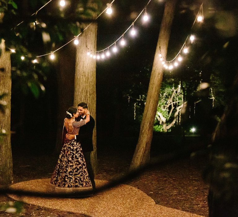 Bride & groom stand beneath twinkling lights on their wedding day