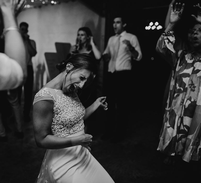 Bride in white Rime Arodaky wedding dress with lace train plays air guitar at evening wedding reception in Dorset