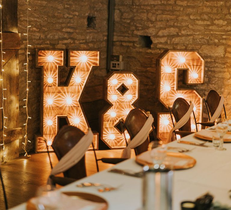 5ft bulb letter signs reading 'K & S' in stone room lit with fairy light strings at Tythe Barn wedding with barn wedding flowers