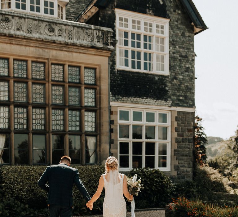 Bride and groom walk through the grounds of Plas Dinam country house