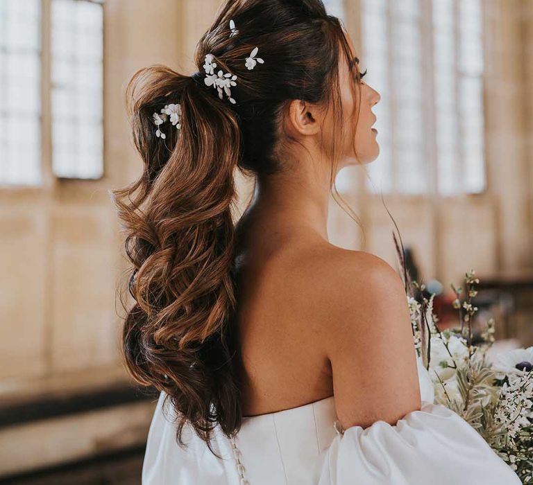 Bride with a full high ponytail decorated with flower hair clips 