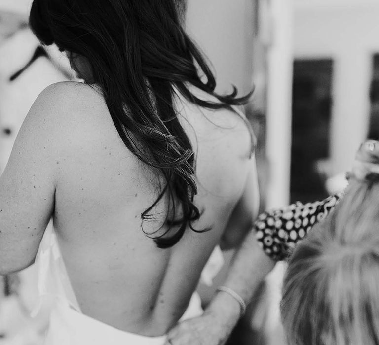 Black and white portrait on the wedding morning of the bride putting on her wedding dress