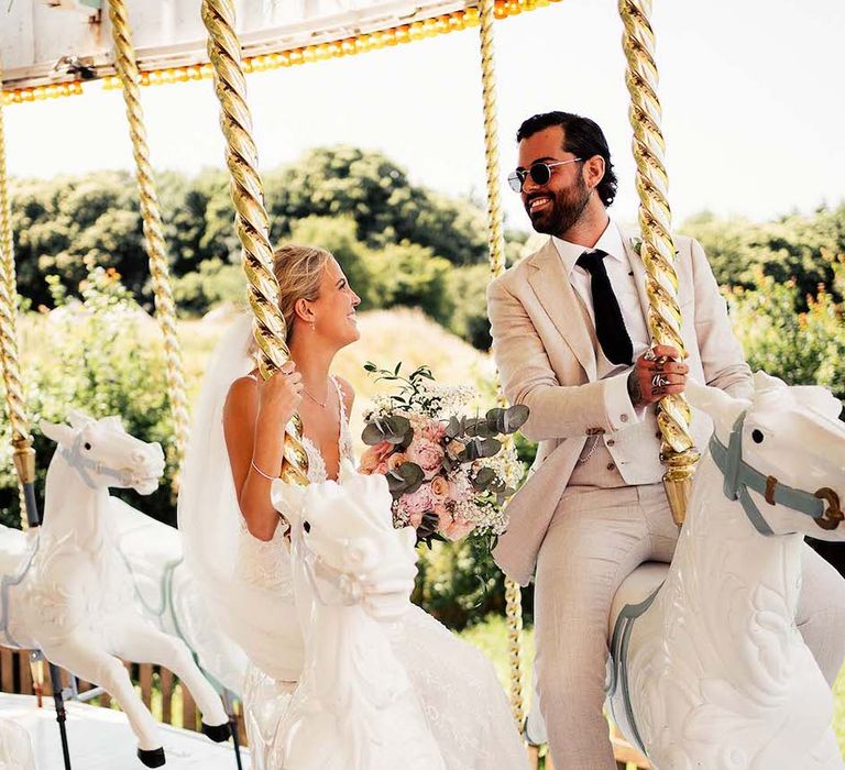 Bride and groom on carousel at Preston Court venue in Kent