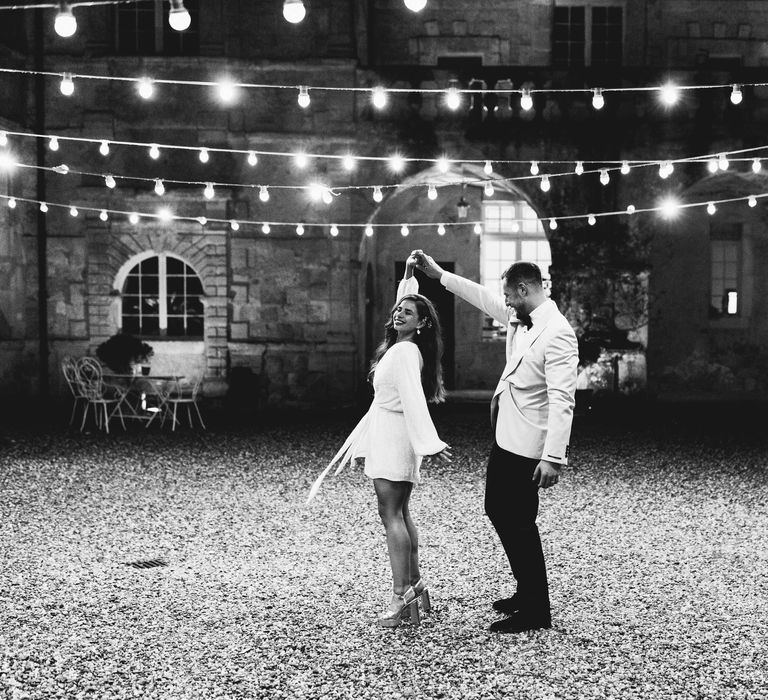 Groom spins his bride around in short white wedding dress 