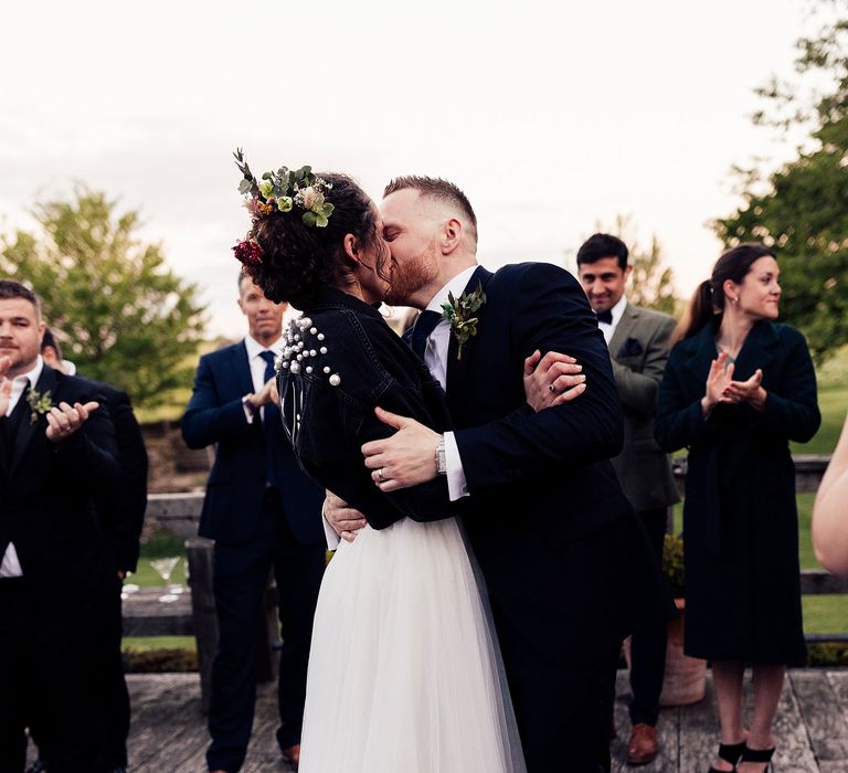 Bride in personalised leather jacket kisses groom