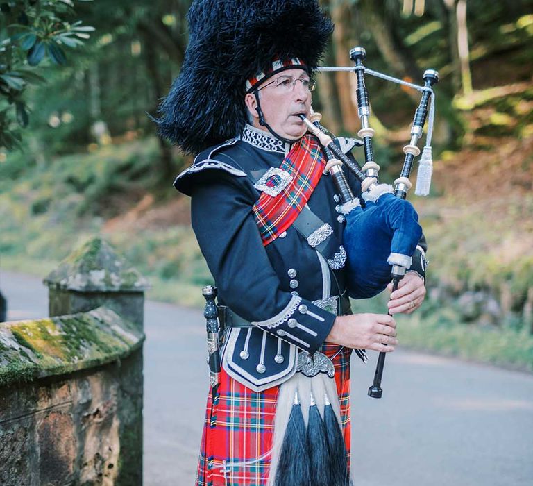 Scottish wedding with bag piper in a red tartan kilt 