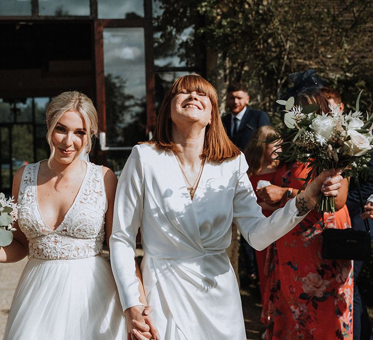 Brides celebrate as they exit ceremony at The Great Tythe Barn venue