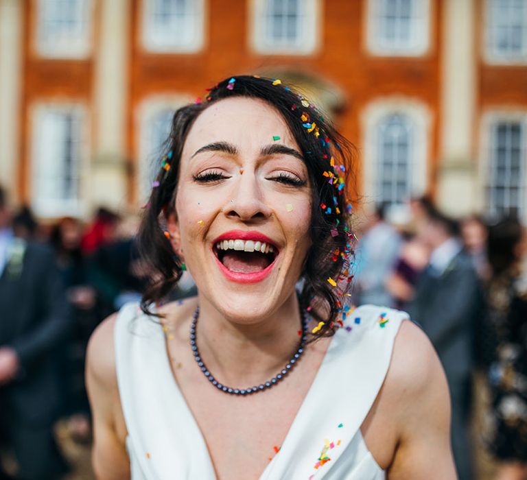 Bride laughs and smiles as confetti is thrown around her