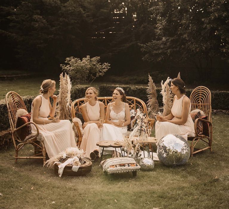 Bridesmaids sit outdoors next to disco balls with a 70s vibe