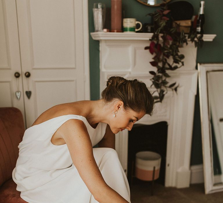 Bride in a Charlie Brear wedding dress putting on her Loeffler Randall plissé-organza sandals