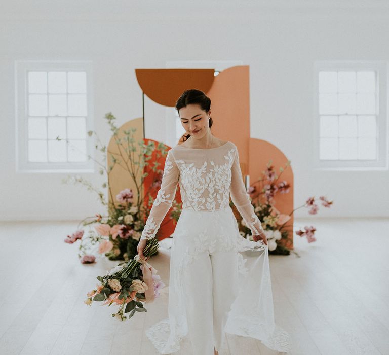 East Asian bride in a bridal jumpsuit with embroidered long sleeves and sheer train 