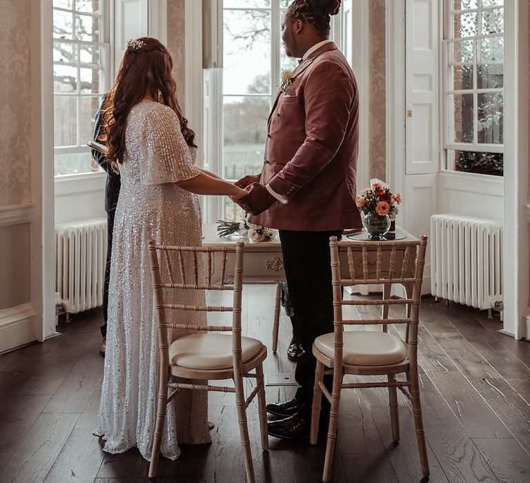 Bride & groom look lovingly at one another whilst holding hands during ceremony 