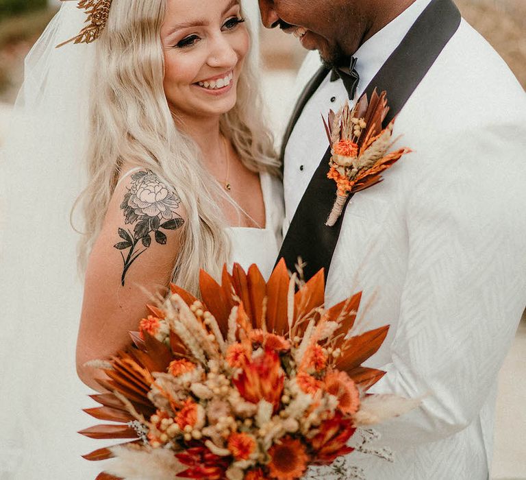 Bride wears gold wedding crown and holds orange wedding bouquet