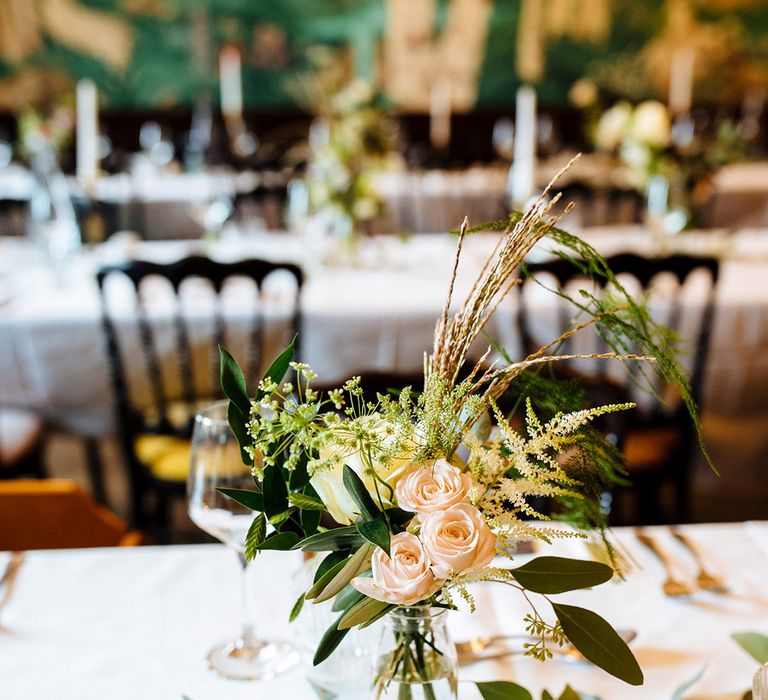 Tablescape with milk bottle vases with roses and green foliage on white tablecloths 