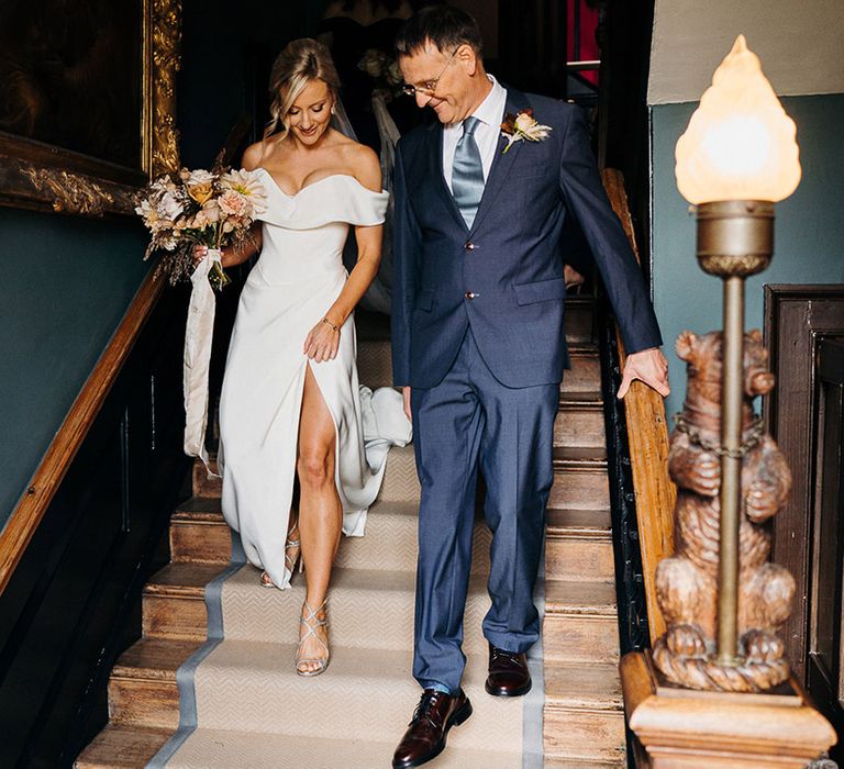 Father of the bride in blue suit and tie walks with his daughter down stairs at Elmore Court 