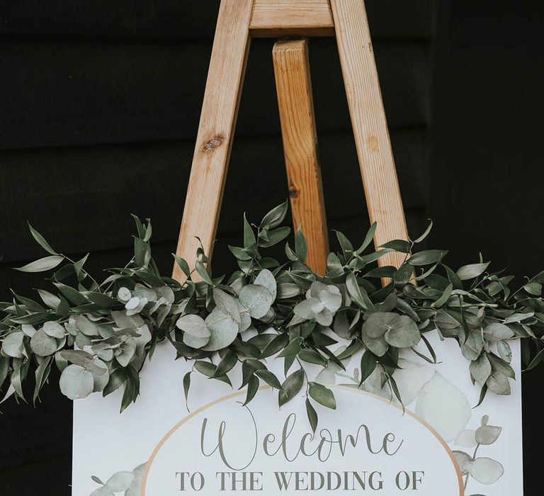 Wedding welcome sign with leaf design and real decorative foliage with funny crossed out dates to celebrate their big day after covid