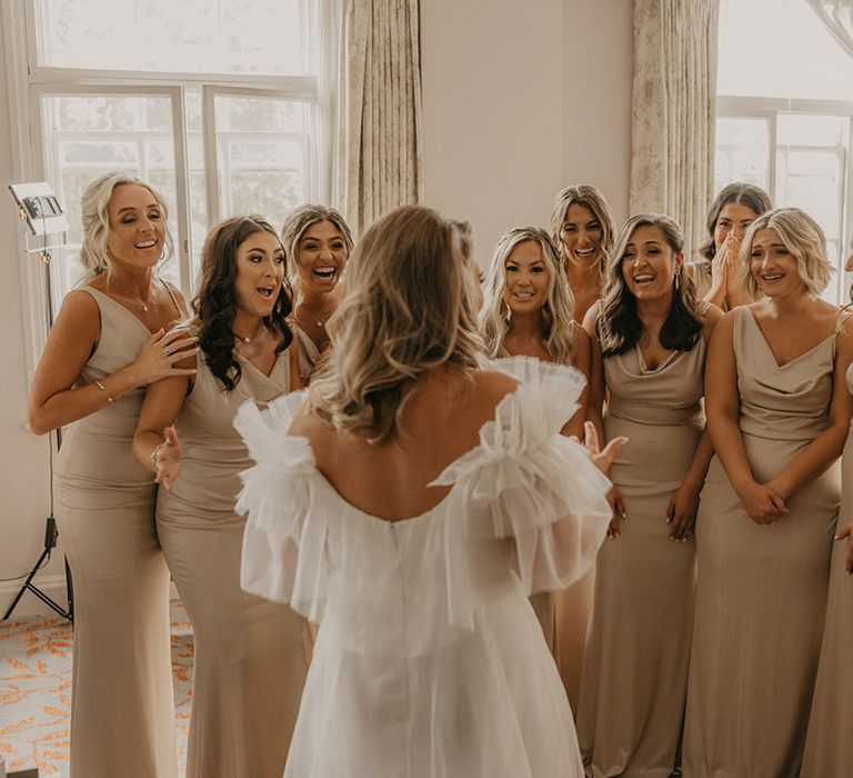 Bride comes out in her ruffle Halfpenny London wedding dress and the bridesmaids all react in gold cowl neck satin dresses