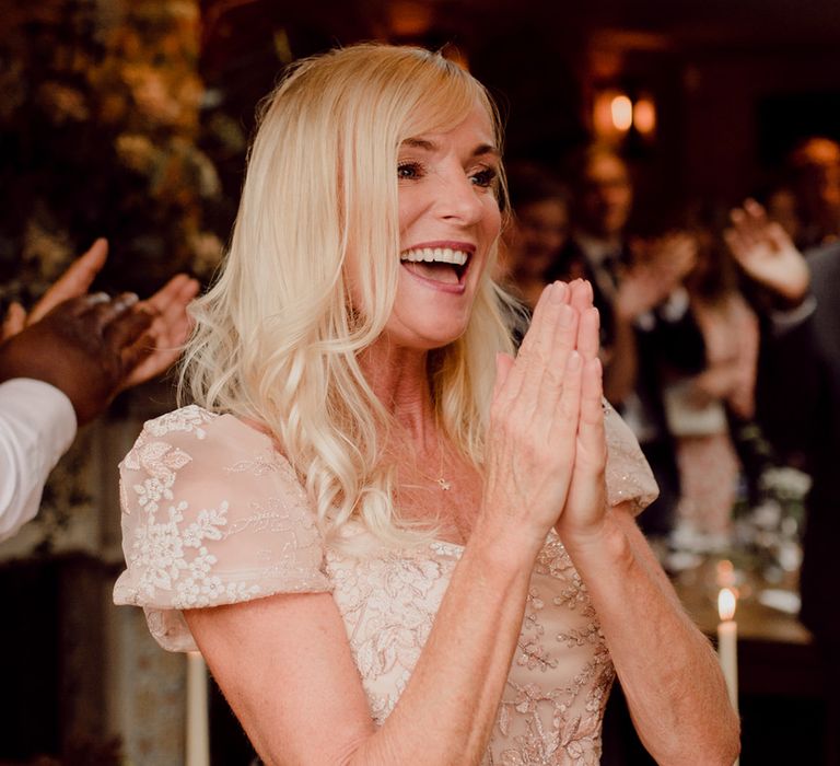 Mother of the bride in sparkly embroidered gold dress looks happy