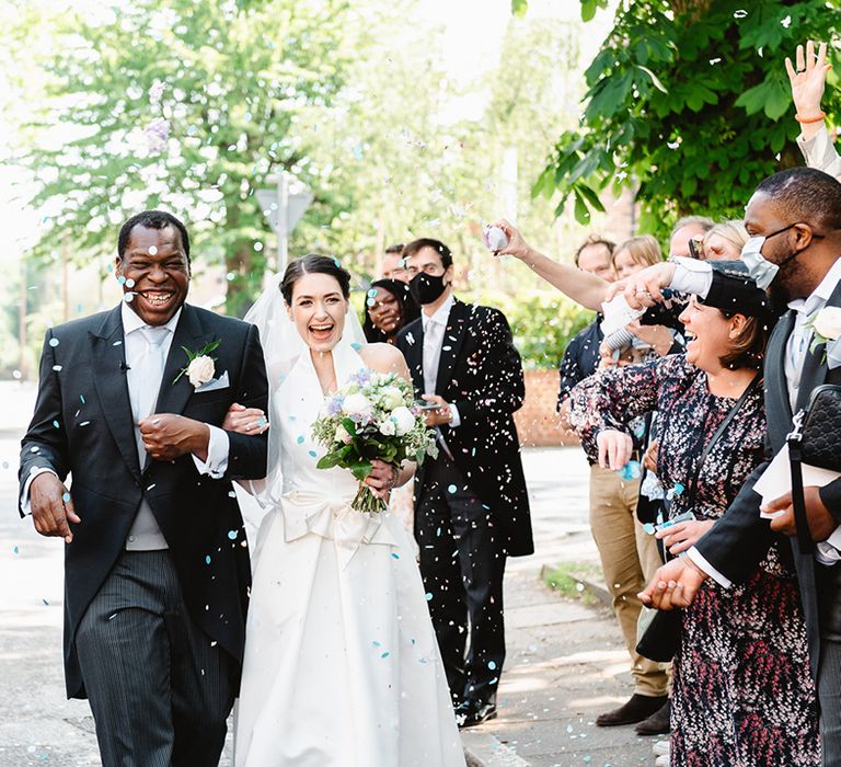 Morning suit with tails worn by groom with baby blue tie and bride in halter neck wedding dress with large bow