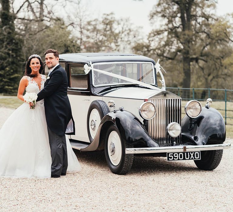 Bride and groom stand in front of their classic 1937 Rolls Royce wedding car transportation 