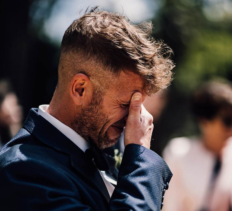 Groom covers his face as he starts crying when he sees the bride 