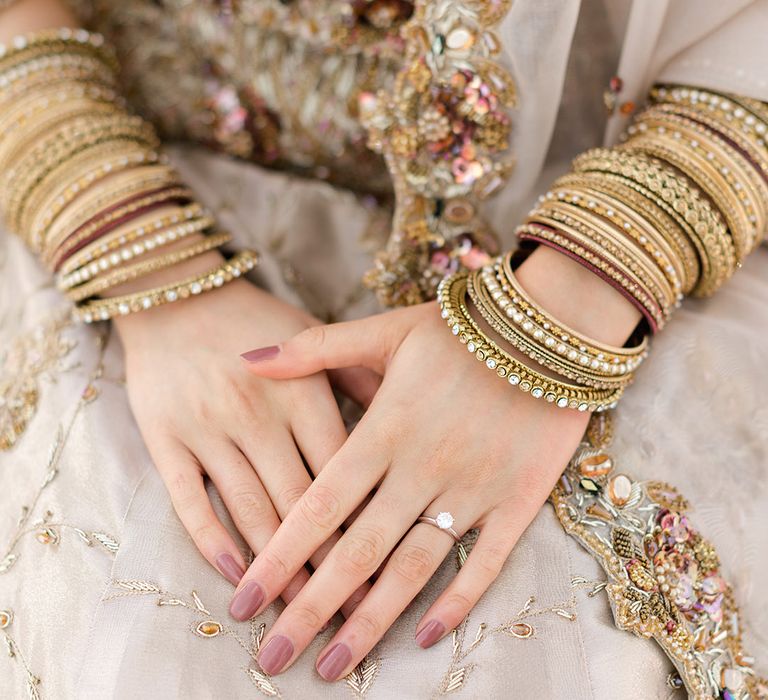 Bride wears gold bangles and purple nail varnish complete with diamond wedding ring 