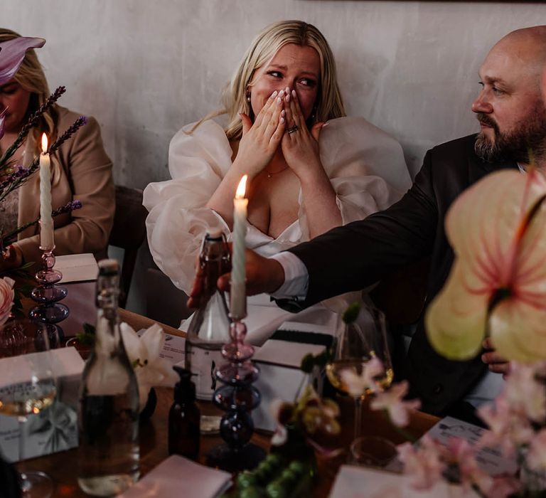 emotional bride in long sheer sleeve wedding dress at wedding reception 