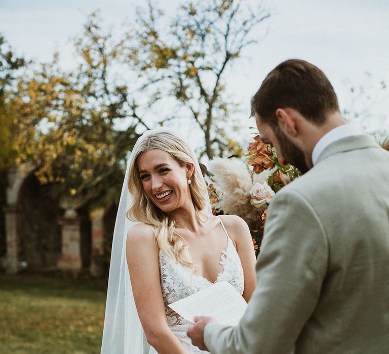 Bride wears Annoushka pearl drop earrings, Made With Love veil in her long blonde hair, and strappy lace Emmy Mae Bridal wedding dress 