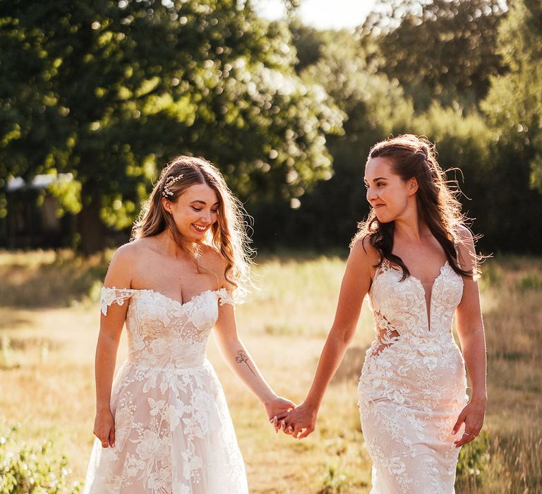 Brides walk hand in hand during golden hour as they walk around the grounds of The Dreys wedding venue 