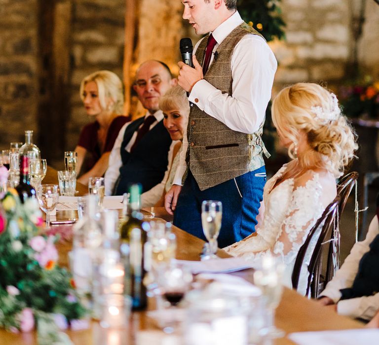 Groom wears tartan suit and maroon tie as he gives speech at The Tithe Barn during reception 