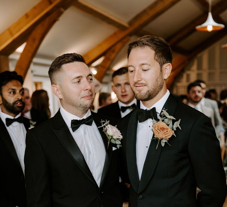 Best man stands with the groom in black tie as they wait for the bride 