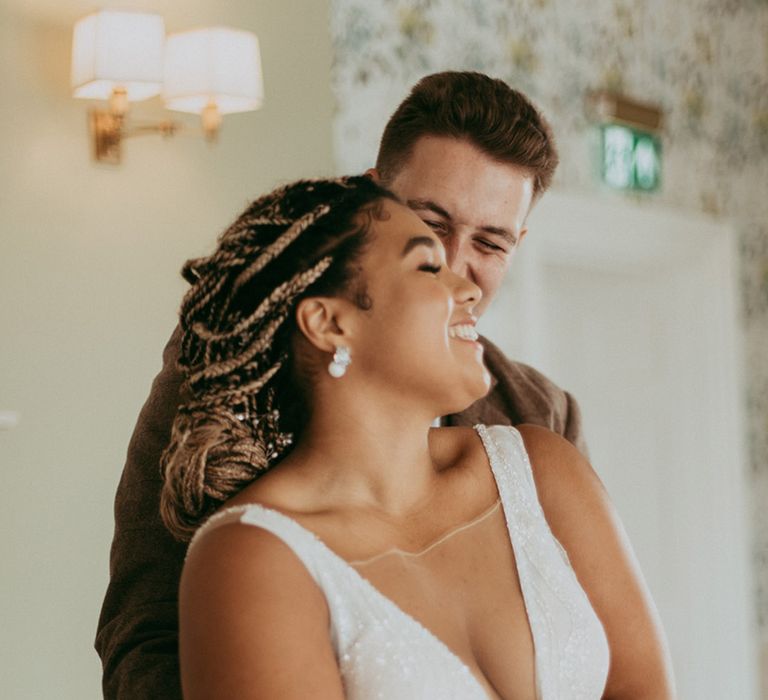 Groom embraces the bride from behind in a sparkly deep v-neck wedding dress 