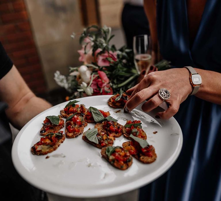 Guests taking small bruschetta canapés from sharing board at stylish wedding