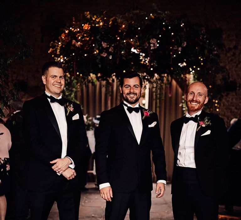 The groom stands with his groomsmen in matching black tuxedos for the wedding 