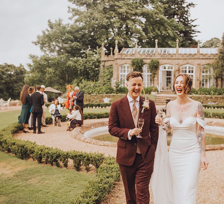 Bride & groom hold champagne outdoors at St Audries Park wedding venue