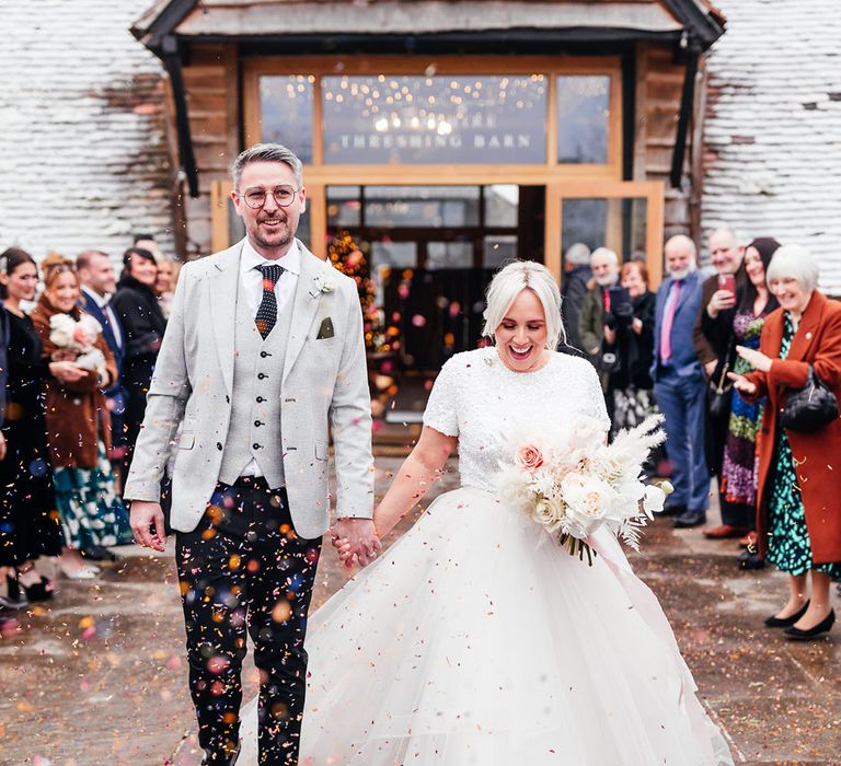 Bride in tulle bridal separates walking with the groom in a light grey suit jacket and waistcoat and spotted tie with black trousers 