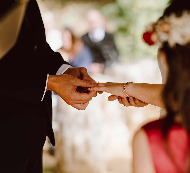 Bride and groom exchanging wedding rings at outdoor wedding venue 