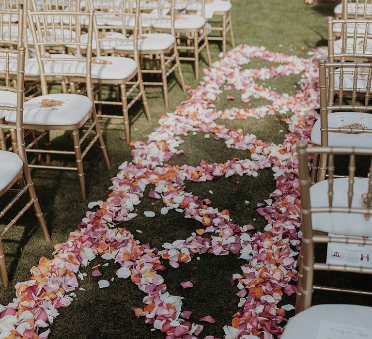 Pink, red, white and orange rose and carnation petals down the aisle at castle wedding venue at 3 day destination multicultural wedding 