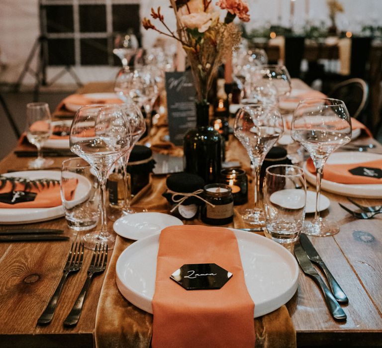 wedding table decorations with burnt orange napkins and black name place cards with wildflower stems in vases