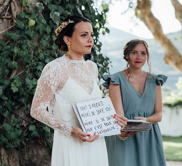 Bride in a lace wedding dress sharing her wedding vows on cue cards like Love Actually 