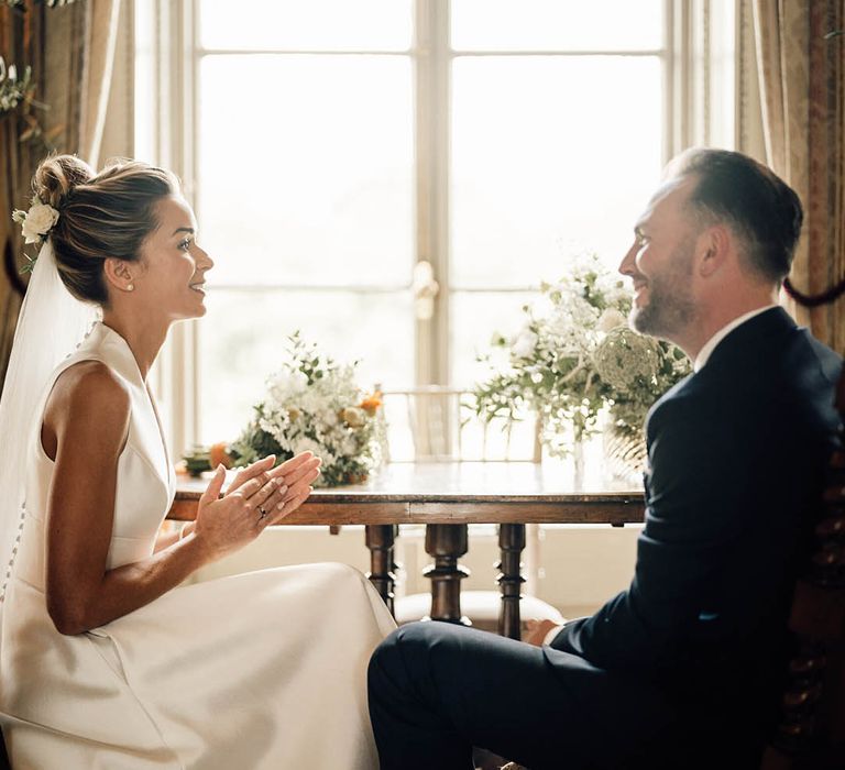 Bride in classic Sheila Harding wedding dress sitting with groom for their country house wedding 