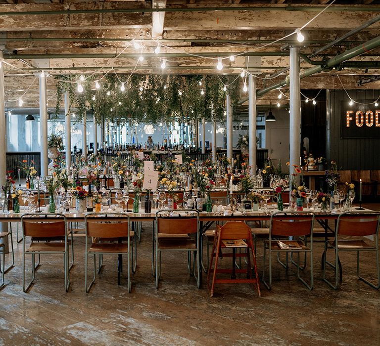 Holmes Mill wedding venue with rows of tables decorated with wildflowers and hanging festoon lighting 