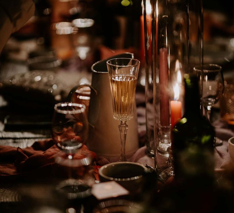 Rustic luxe wedding tablescape with long pink and purple tapered candles, tall candle glass jars, flower and foliage centrepieces and retro wedding signage 