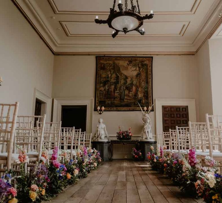 Reception room of Elmore Court Gloucestershire wedding venue with spring flowers down the aisle and chandelier lighting