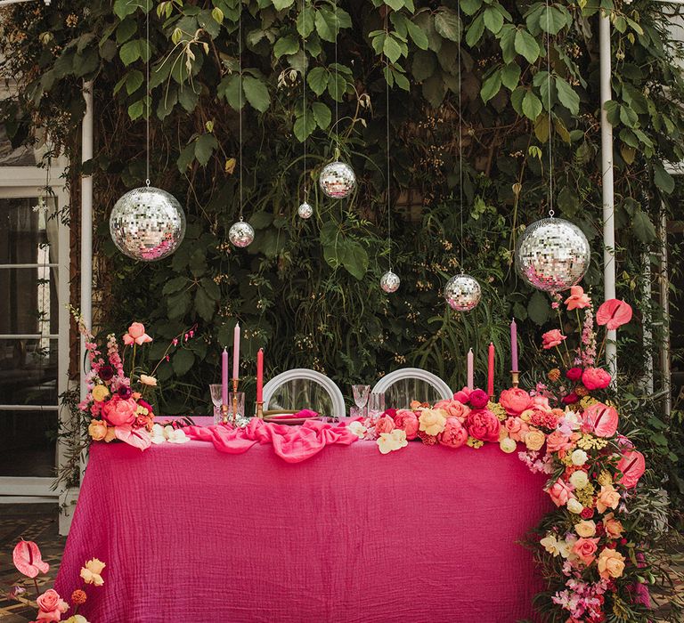 Sweetheart table with hanging disco balls and pink decorations 