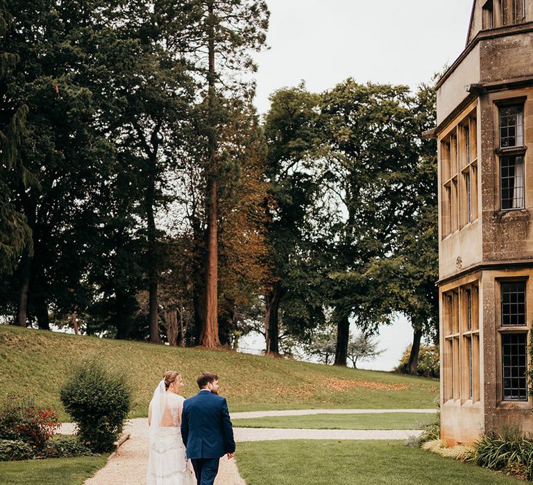 Coombe Lodge wedding venue with the bride in a delicate lace wedding dress and groom in blue suit 