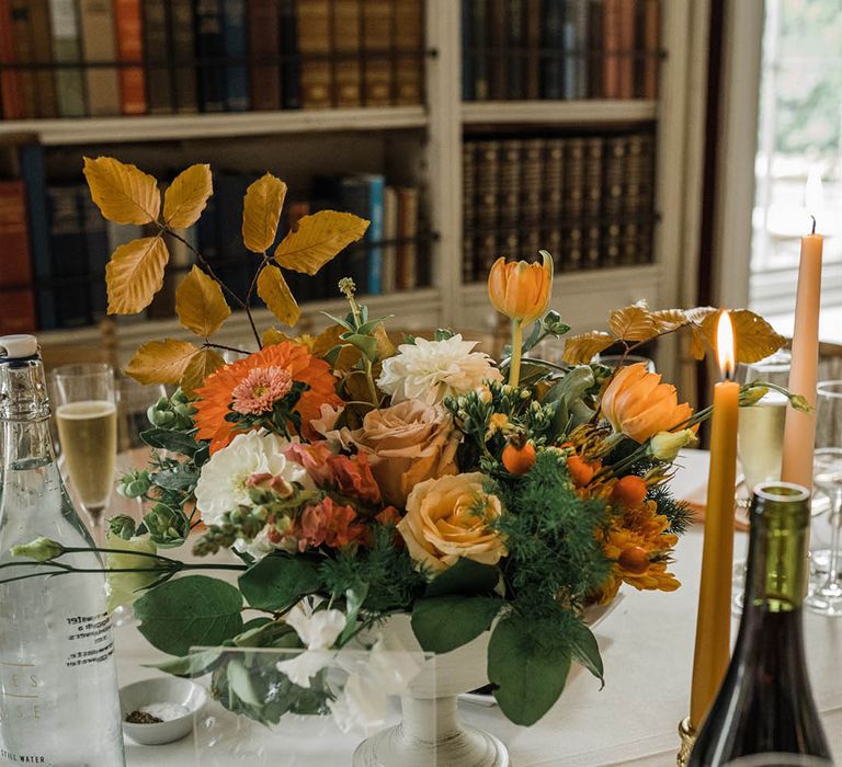 White bowl wedding table centrepiece with orange and yellow wedding flowers at library wedding 