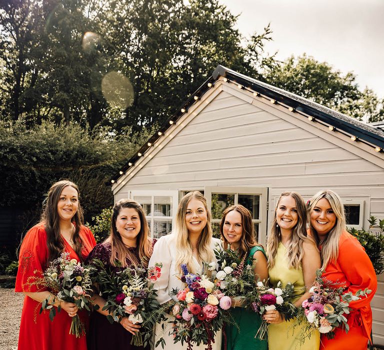 Bridesmaids in colourful bridesmaid dresses in shades of orange, yellow and green for boho wedding 