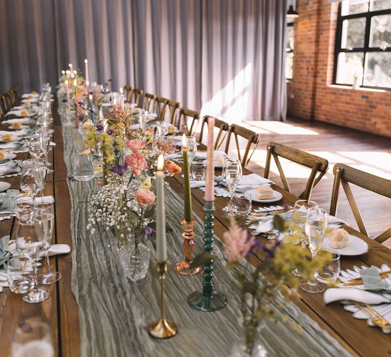 Pastel wedding theme tablescape with sage green table runner, flowers and bud vases 