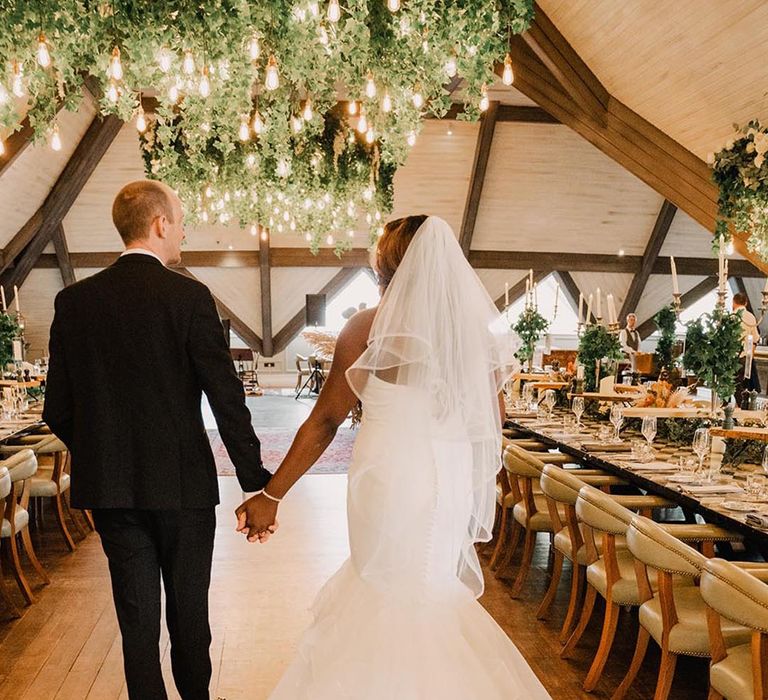 Bride in mermaid fishtail wedding dress with groom in black tuxedo 